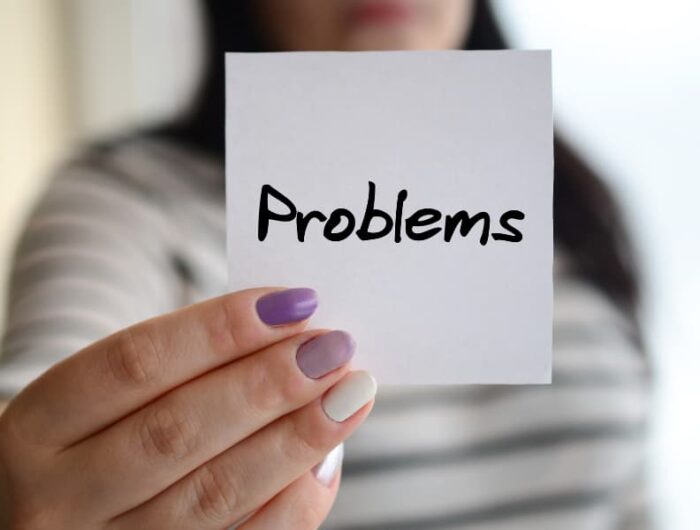 a womans hand holding post-it that that says problems on it