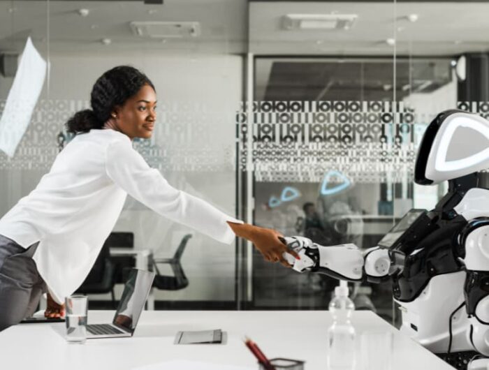 Smiling African American woman shaking hands with a robot.